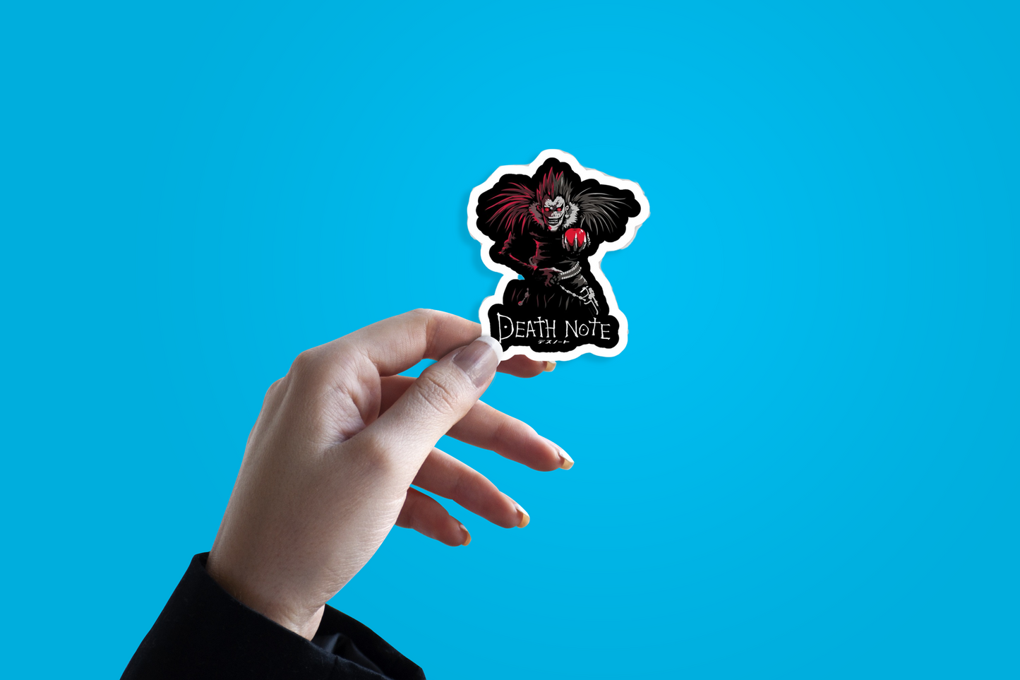 Hand holding a 'Death Note' sticker against a blue background