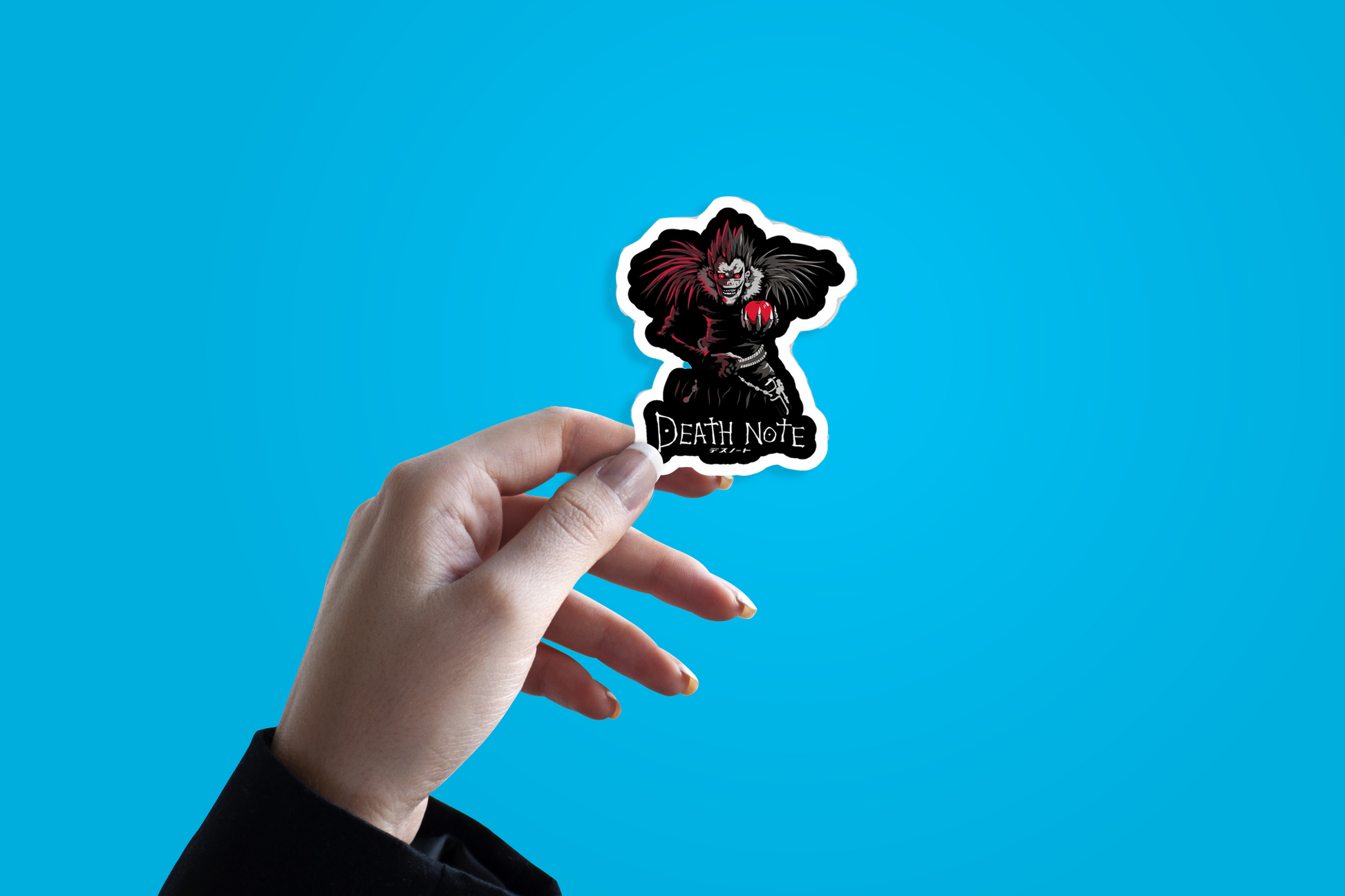 Hand holding a 'Death Note' sticker against a blue background